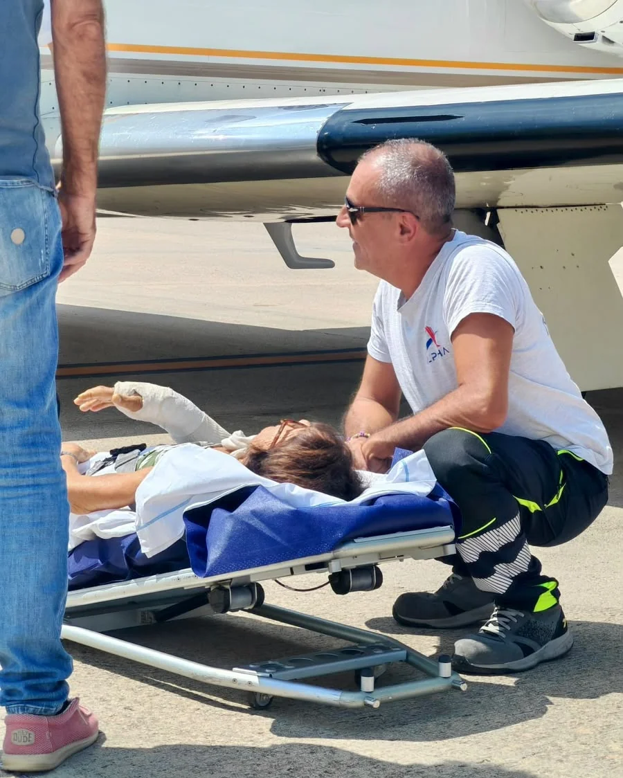 Sergio, operatore ALPHA, accanto a una paziente in barella sulla pista dell'aeroporto di Olbia, prima dell'imbarco su un volo sanitario