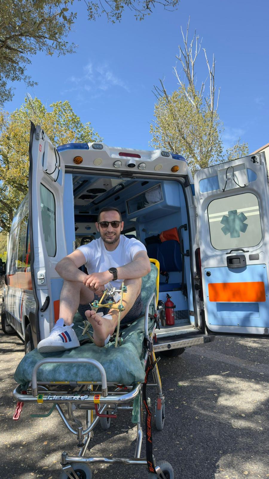 Un paziente sorridente seduto sulla barella davanti alla nostra ambulanza attrezzata
