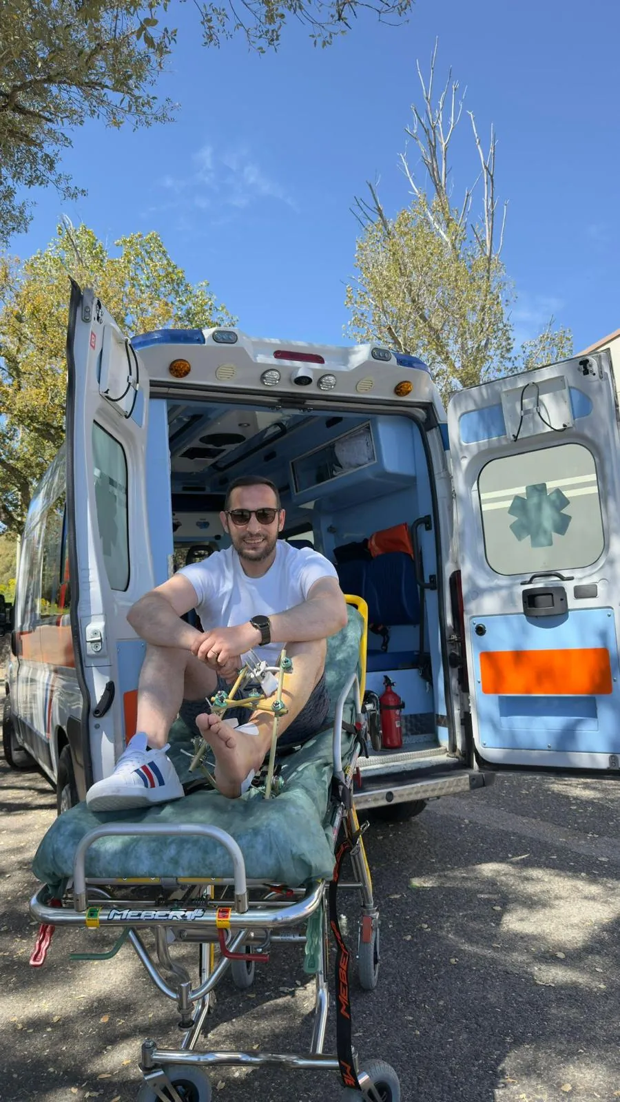 Un paziente sorridente sulla barella davanti all'ambulanza ALPHA attrezzata