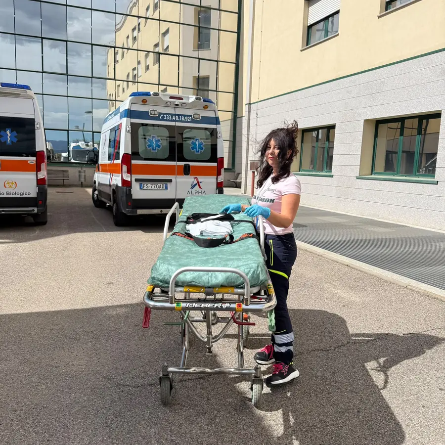 Operatrice ALPHA con la barella preparata accanto all'ambulanza pronta per il servizio