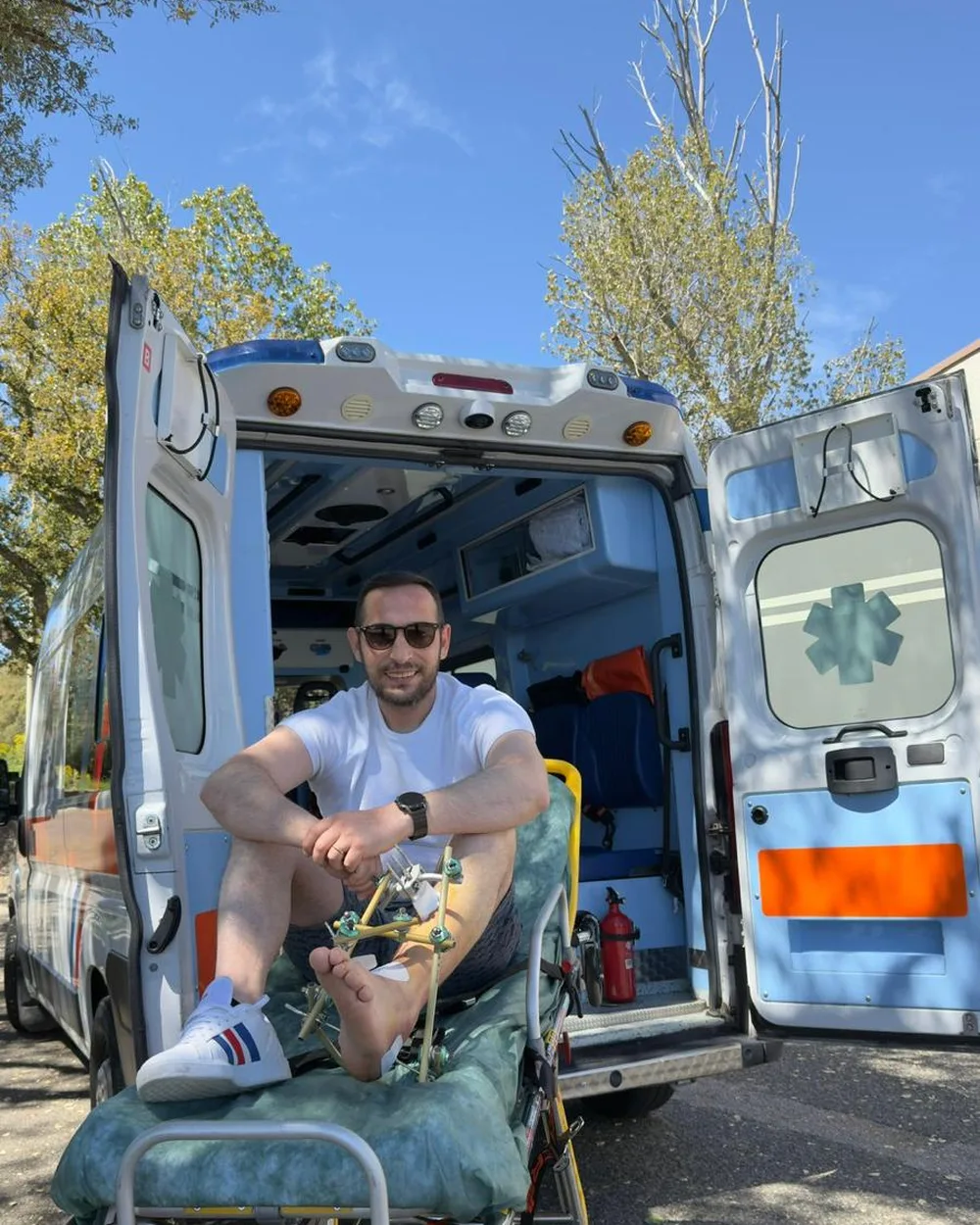 Un operatore ALPHA seduto nel vano posteriore dell'ambulanza con le porte aperte, accanto alla barella