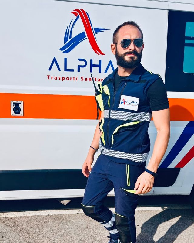 Andrea, autista soccorritore ALPHA, in divisa davanti all'ambulanza