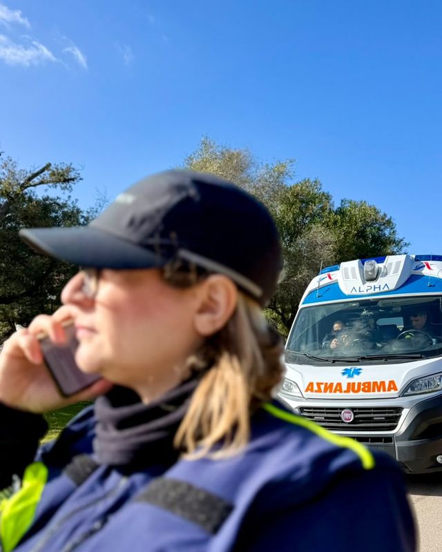 Cinzia, soccorritrice ALPHA, al telefono per organizzare un servizio con l'ambulanza alle spalle
